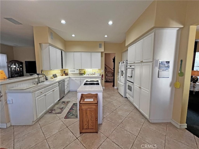 kitchen with sink, light tile patterned floors, white cabinetry, stainless steel appliances, and kitchen peninsula