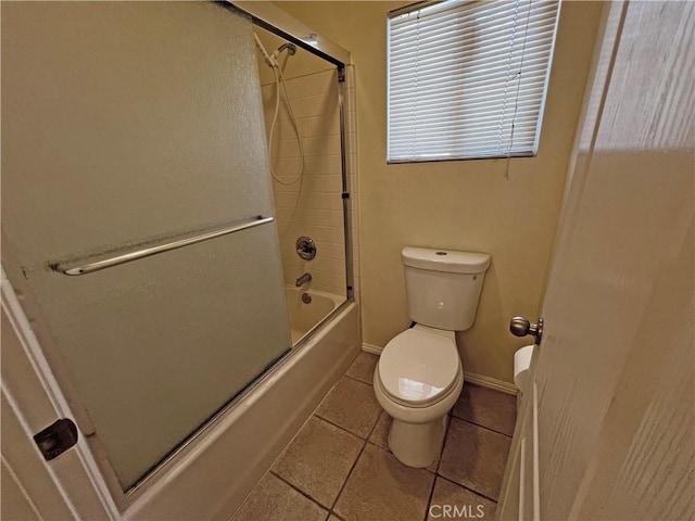 bathroom with tile patterned floors, toilet, and combined bath / shower with glass door