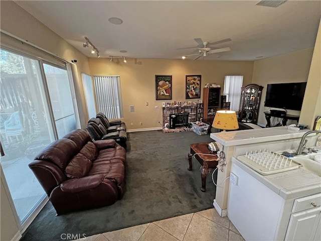 tiled living room featuring ceiling fan and a fireplace