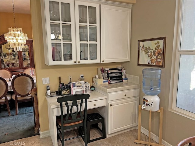 home office featuring built in desk, an inviting chandelier, and light tile patterned floors