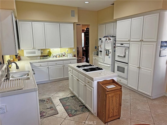 kitchen featuring sink, white cabinetry, a center island, light tile patterned floors, and white appliances