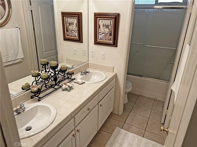 full bathroom with toilet, tile patterned floors, vanity, and shower / bath combination with glass door