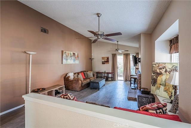 living area with dark wood-style flooring, visible vents, vaulted ceiling, and a textured ceiling