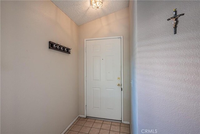 doorway with light tile patterned floors, a textured ceiling, lofted ceiling, and baseboards