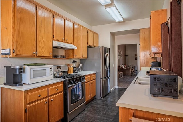 kitchen featuring light countertops, appliances with stainless steel finishes, brown cabinetry, and under cabinet range hood