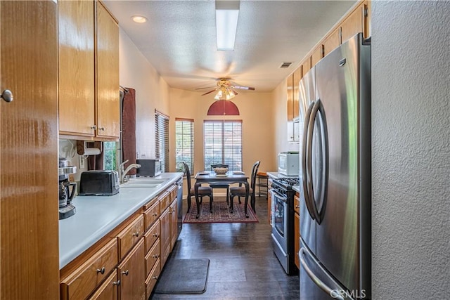 kitchen featuring brown cabinets, dark wood-style floors, stainless steel appliances, and light countertops