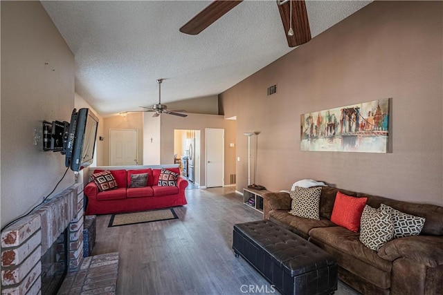 living room featuring visible vents, lofted ceiling, ceiling fan, wood finished floors, and a textured ceiling