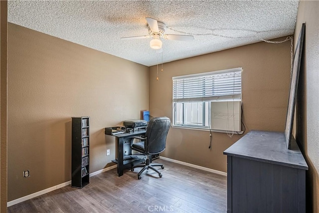 office space featuring ceiling fan, a textured ceiling, baseboards, and wood finished floors