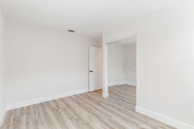 unfurnished bedroom with light hardwood / wood-style floors and a closet