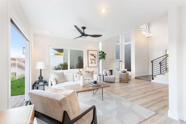 living room featuring ceiling fan with notable chandelier, a water view, and light wood-type flooring