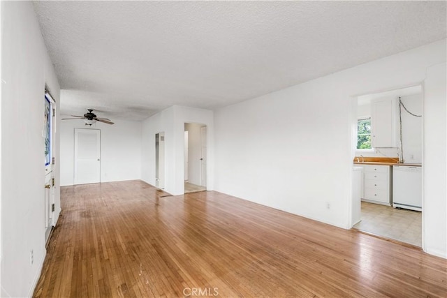 unfurnished living room featuring ceiling fan, a textured ceiling, and light hardwood / wood-style floors