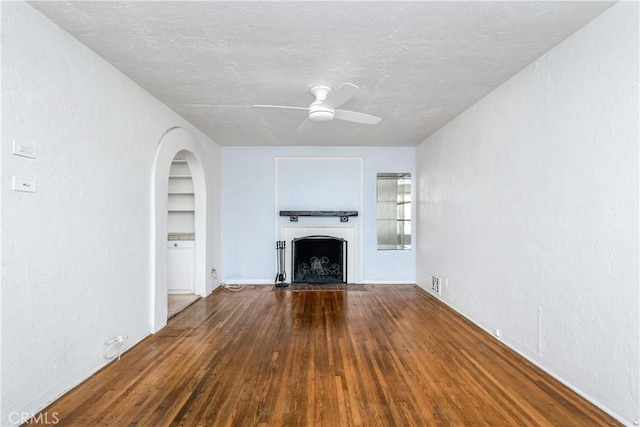 unfurnished living room featuring hardwood / wood-style flooring, ceiling fan, built in features, and a textured ceiling