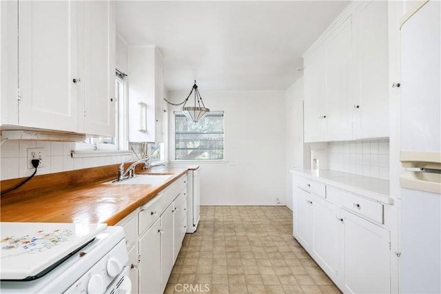 kitchen with white cabinetry, range, sink, and decorative backsplash