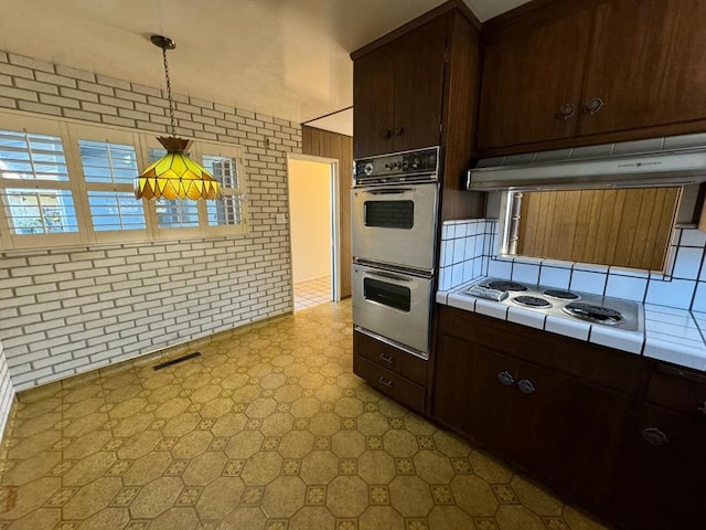 kitchen featuring extractor fan, hanging light fixtures, tile counters, dark brown cabinets, and white appliances