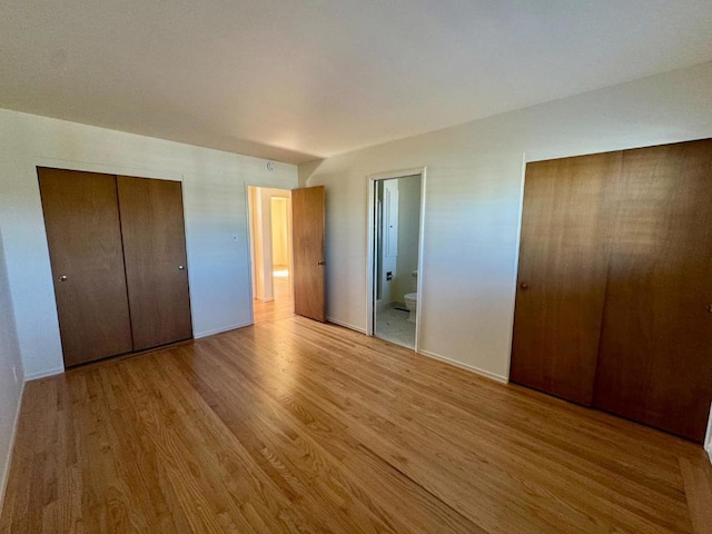 unfurnished bedroom with ensuite bathroom and light hardwood / wood-style flooring