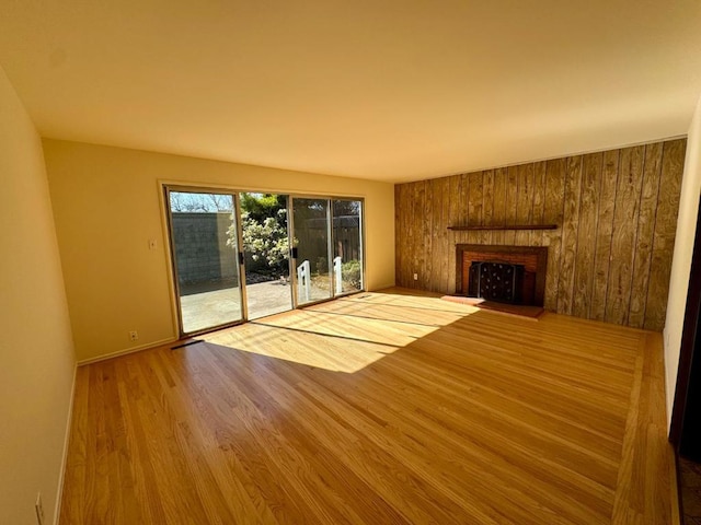 unfurnished living room with hardwood / wood-style flooring and wooden walls