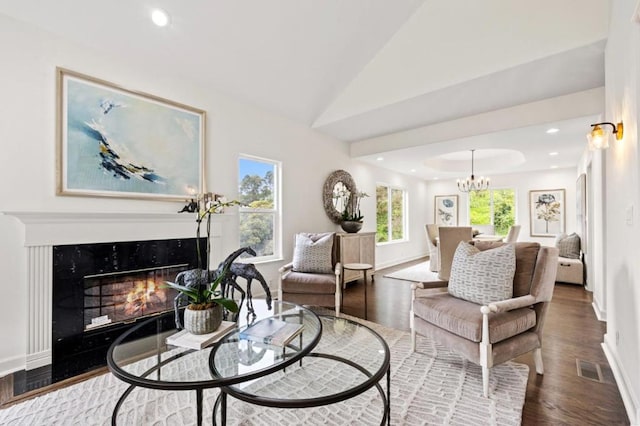 living room with lofted ceiling, hardwood / wood-style floors, and an inviting chandelier