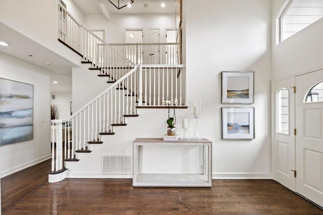 entryway with a towering ceiling and dark hardwood / wood-style flooring