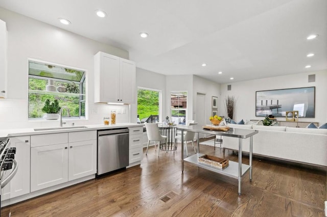 kitchen with sink, appliances with stainless steel finishes, white cabinetry, backsplash, and dark hardwood / wood-style flooring