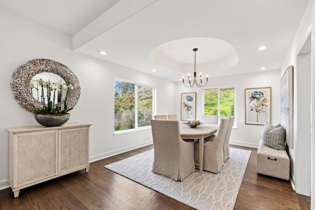 dining area featuring a notable chandelier, a tray ceiling, dark hardwood / wood-style floors, and a healthy amount of sunlight