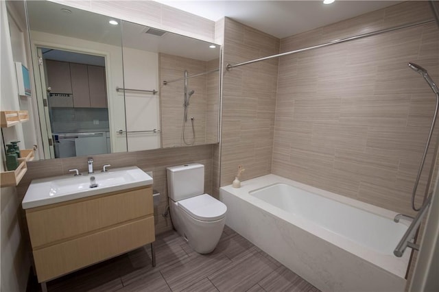 full bathroom featuring tiled shower / bath, tile walls, vanity, and toilet