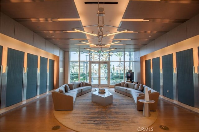 living room featuring wood-type flooring, a chandelier, a wall of windows, and french doors