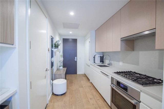 kitchen featuring white cabinetry, sink, light wood-type flooring, and appliances with stainless steel finishes