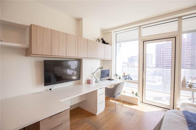 home office featuring built in desk, floor to ceiling windows, and light wood-type flooring