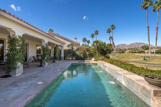 view of pool featuring pool water feature, a mountain view, and a patio