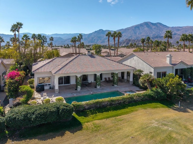 rear view of property with a mountain view, a patio area, and a lawn