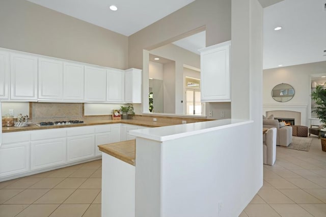 kitchen with white gas cooktop, kitchen peninsula, light tile patterned floors, and white cabinets