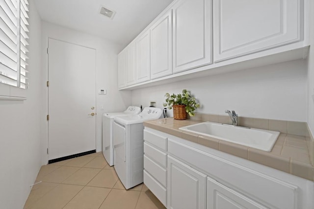 laundry room featuring cabinets, sink, washing machine and dryer, and light tile patterned floors