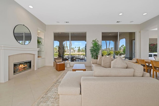 living room featuring a tile fireplace, light tile patterned floors, and built in shelves