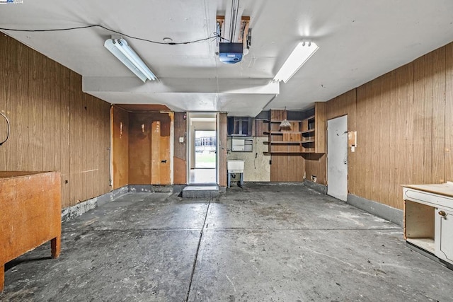 garage featuring a garage door opener, sink, and wooden walls