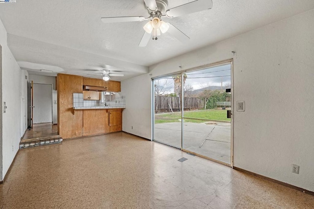 unfurnished living room with ceiling fan and a textured ceiling