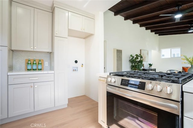 kitchen with beamed ceiling, backsplash, wood ceiling, gas range, and light hardwood / wood-style flooring