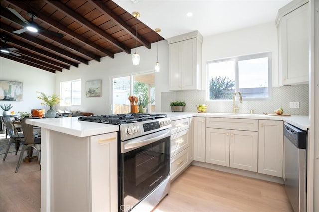 kitchen with sink, appliances with stainless steel finishes, backsplash, decorative light fixtures, and kitchen peninsula