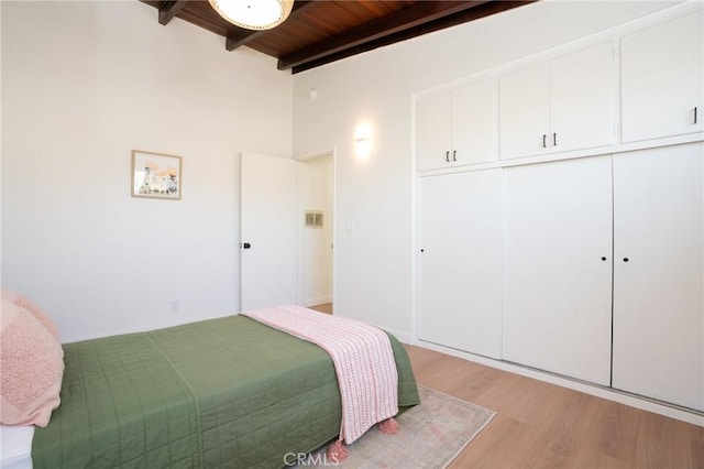 bedroom with wood ceiling, light hardwood / wood-style flooring, a closet, and beamed ceiling