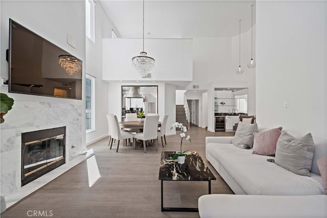 living room with wine cooler, a notable chandelier, a high end fireplace, and wood-type flooring