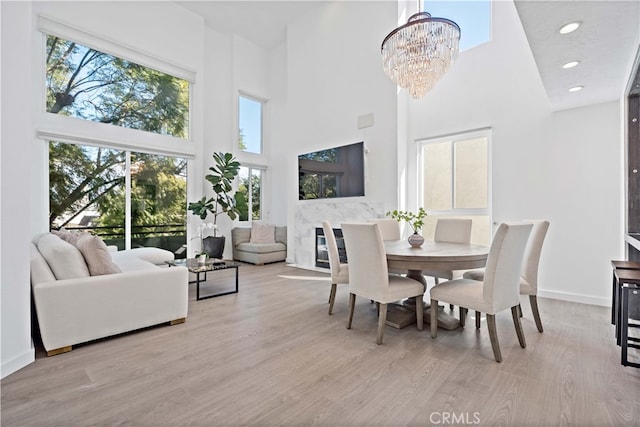 dining space featuring a towering ceiling, a chandelier, and light wood-type flooring