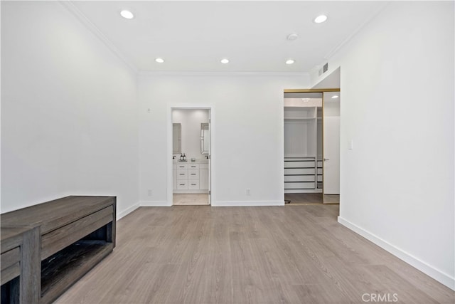 bedroom featuring connected bathroom, ornamental molding, light hardwood / wood-style floors, and a closet