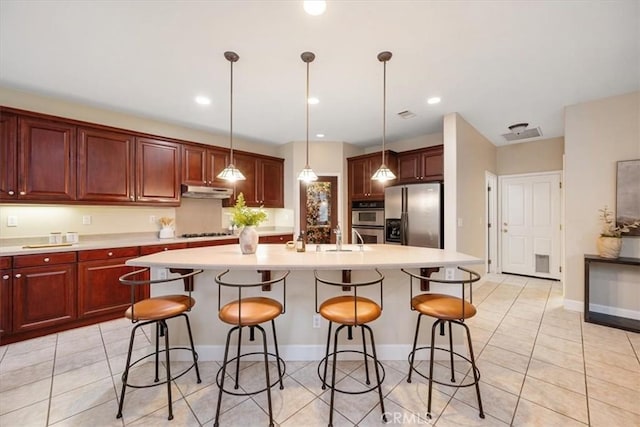 kitchen with pendant lighting, a center island with sink, and appliances with stainless steel finishes