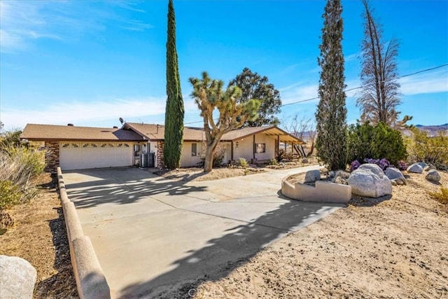 single story home with central AC unit and a garage