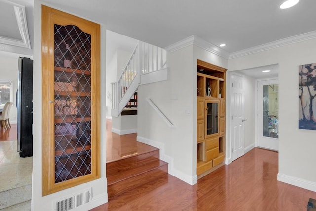 staircase with crown molding and hardwood / wood-style flooring