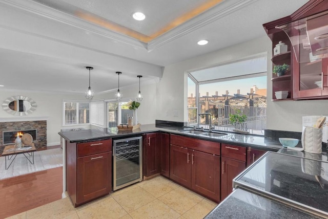 kitchen with wine cooler, a stone fireplace, sink, crown molding, and kitchen peninsula