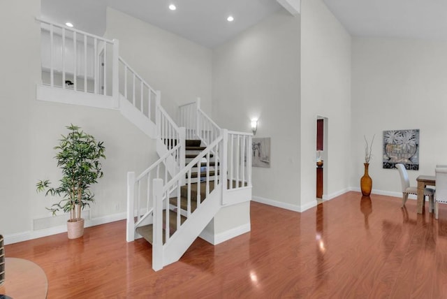 staircase with wood-type flooring and a high ceiling