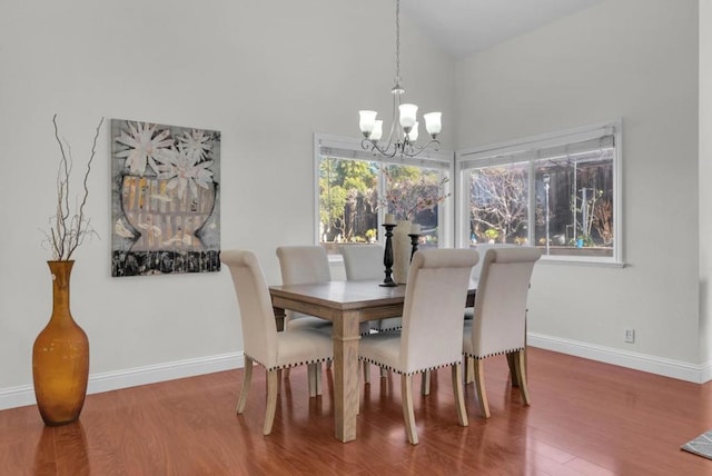 dining area with an inviting chandelier, high vaulted ceiling, and hardwood / wood-style flooring