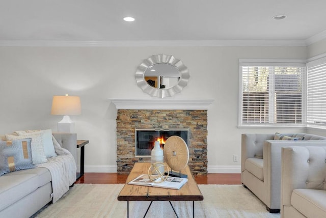 living room featuring crown molding, a stone fireplace, and hardwood / wood-style floors