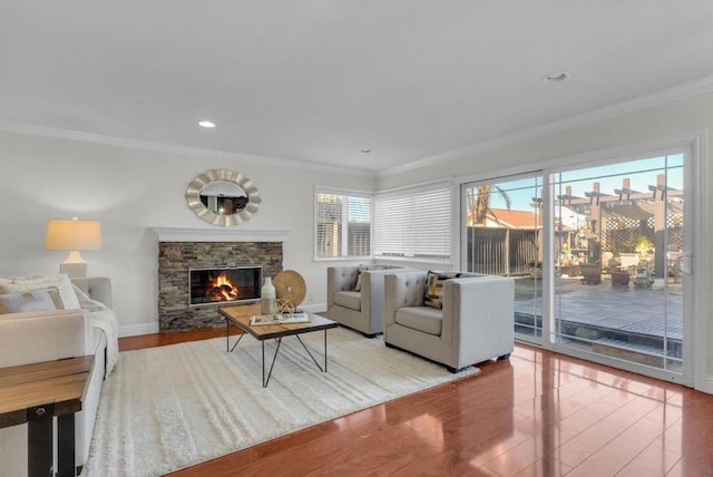 living room featuring hardwood / wood-style flooring, a stone fireplace, and ornamental molding