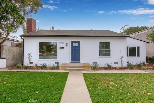 view of front of home featuring crawl space, a chimney, a front lawn, and stucco siding